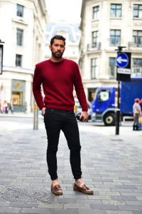 Мужчина в темно-красном свитере и темных джинсах на улице