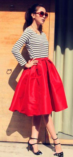Девушка в красной, пышной юбке миди, полосатом топе и туфлях на каблуке