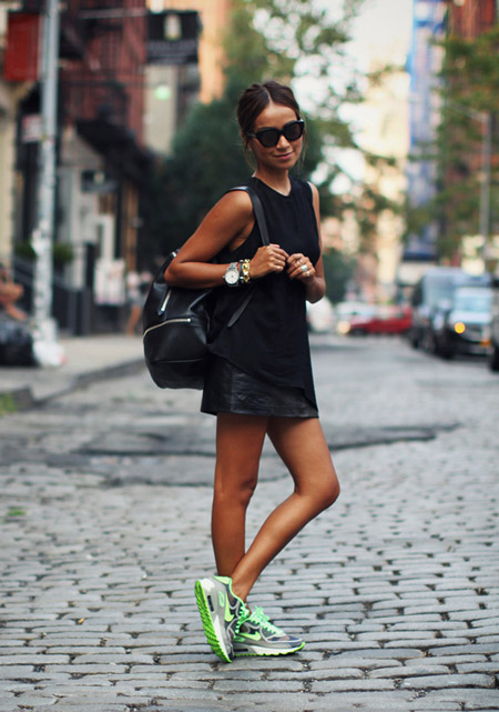Девушка в черной, кожаной, спортивной юбке, черном топе и кроссовках