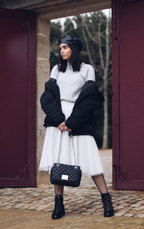 Девушка в белой юбке из фатина, свитере, черном пуховике и армейских ботинках фото