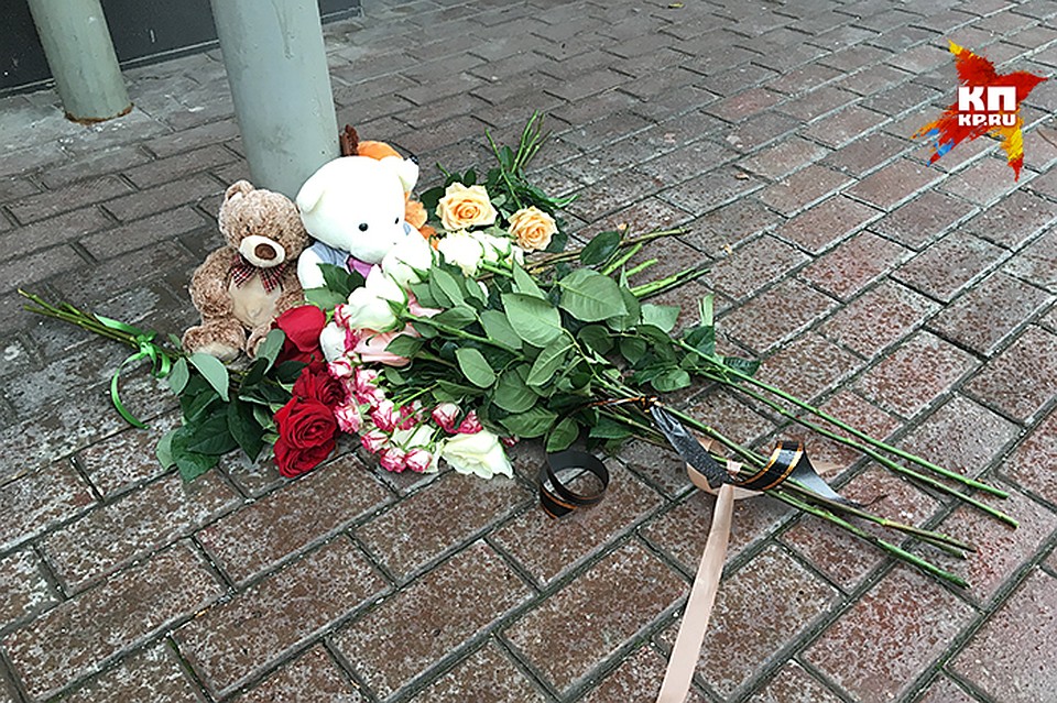 У подъезда, на месте, куда упал мальчик, лежат несколько букетов цветов, мягкие игрушки Фото: Александр РОГОЗА