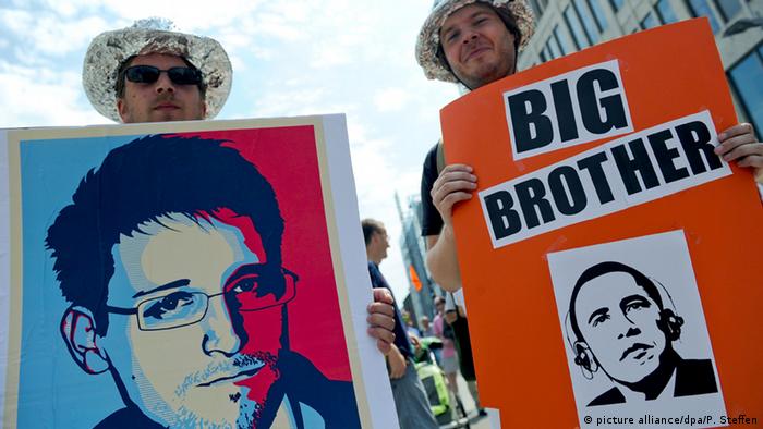 Протестующие держат плакаты с портретом Эдварда Сноудена